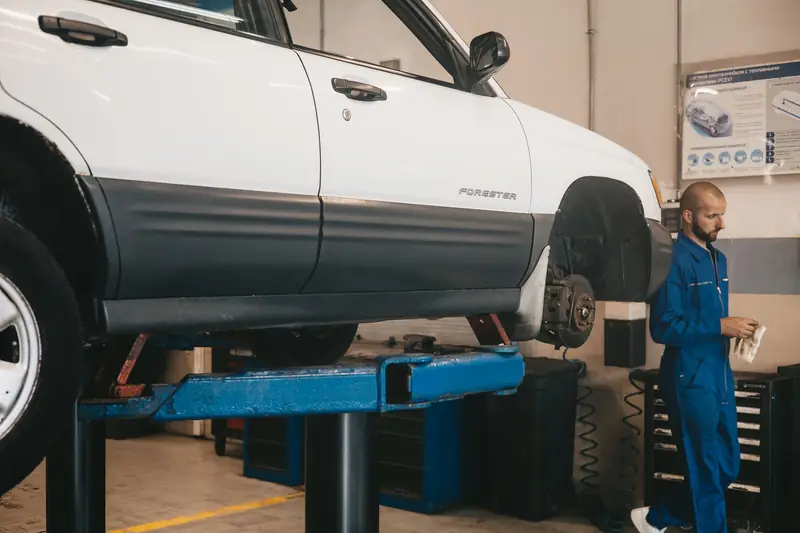 Mecanicien in blauwe overall controleert een wagen in een garage