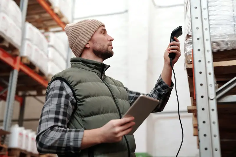 Magazijnmedewerker scant goederen in een palletrek met een handscanner en tablet