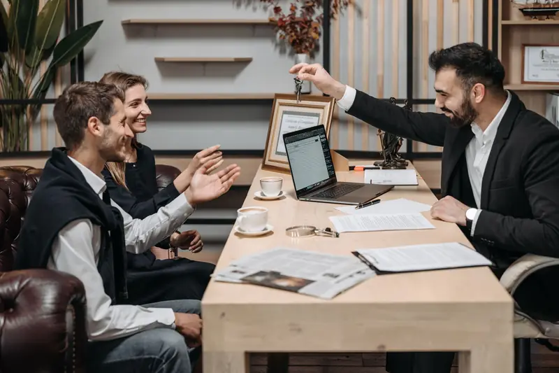 Vastgoedmakelaar overhandigt sleutels aan klanten aan zijn bureau