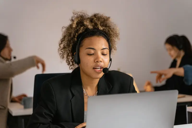 Medewerkster met headset voert een telefoongesprek achter haar laptop